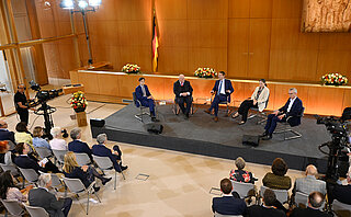 Fünf Referenten des Verfassungsgespräch 2023 sitzen vor einem Plenum und diskutieren.