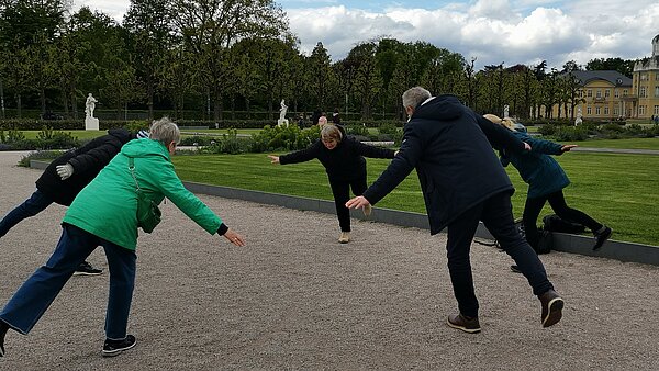 Personen vor dem Schloss Karlsruhe, die Gleichgewichtsübungen ausführen