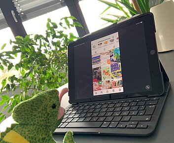 Stoffchamäleon stitzt vor einem Tablet