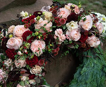 Blumenkranz an Grabstein lehnend