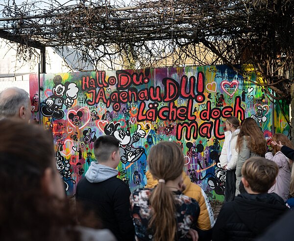 Schüler betrachten die neugestaltete Wand bei der feierlichen Einweihung im Weiherhofgrünzug. 
