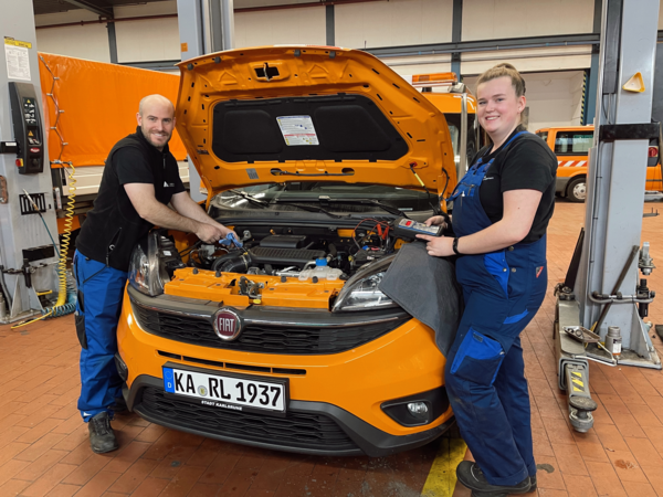 Azubi und Ausbilder an einem Auto