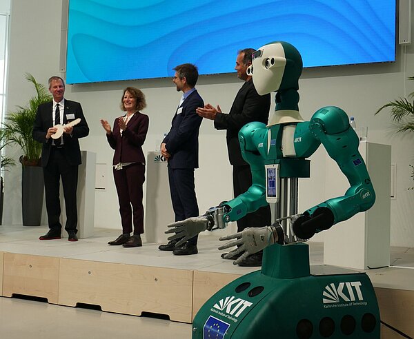 Ein Roboter übergibt den Schlüssel für das neue KIT-Gebäude am Adenauerring.