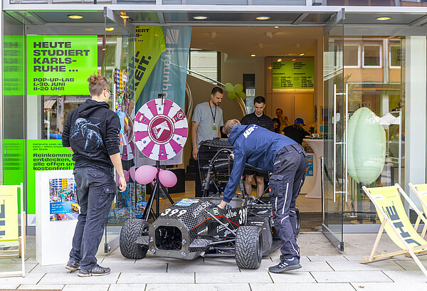 HKA Mitarbeitende transportieren einen Rennwagen in das POP-UP-LAB
