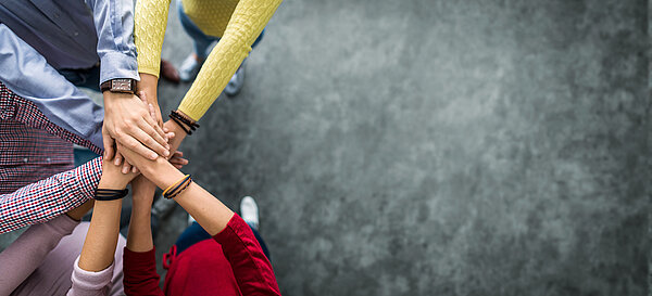 Foto von mehreren Händen, die miteinander einschlagen.