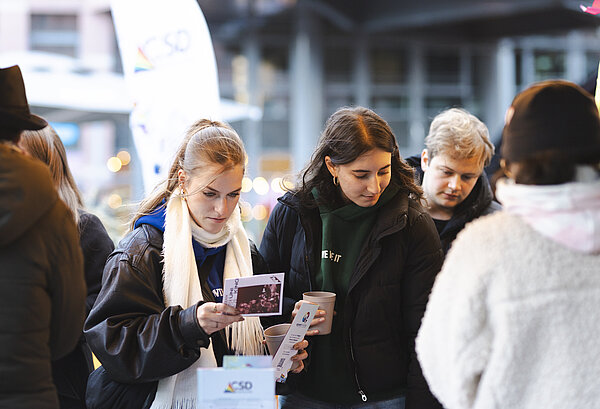 Junge Menschen schauen sich Werbematerialien an einem Stand an