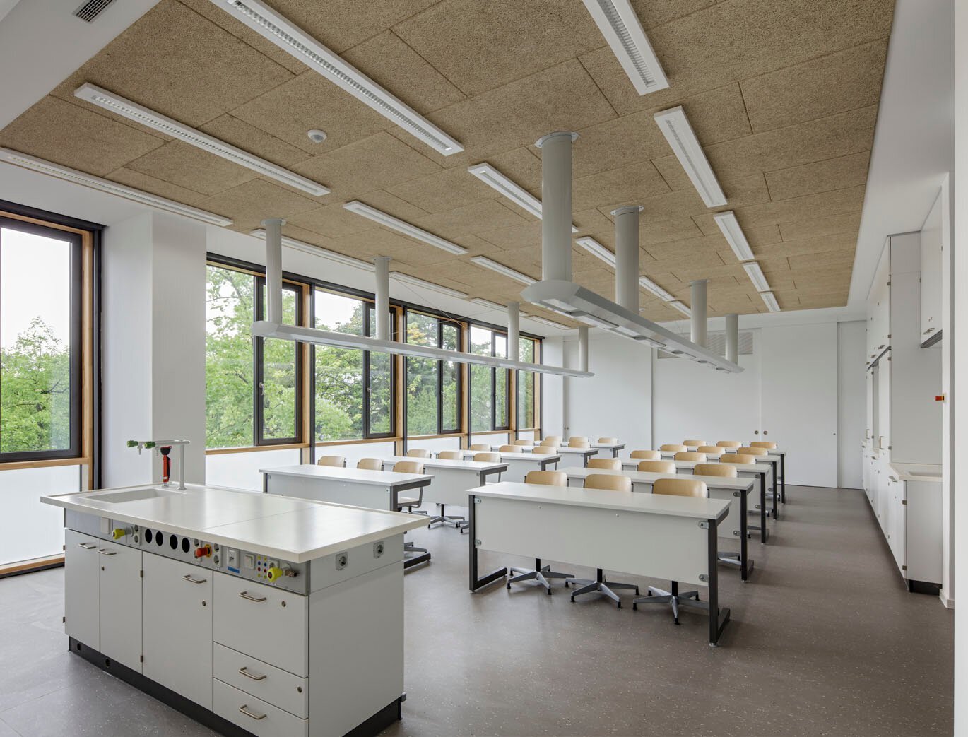 Das Bild zeigt einen sanierten Fachraum mit Tischreihen sowie einem Lehrertisch mit Waschbecken.