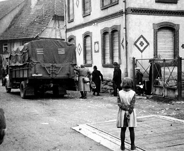 Deportation der Familie Maier aus Kippenheim. Mit einem schweren Koffer geht Siegfried Maier (1897–1958) aus dem Tor, vor ihm sein zehnjähriger Sohn Kurt (geb. 1930) mit seiner Schultasche.