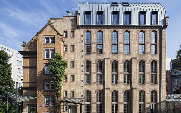 Blick auf die Nordansicht des Bestand mit neu aufgestocktem Tonnendach in Titanzinkdeckung und passenden Fenstergauben mit außenliegenden Rollos.