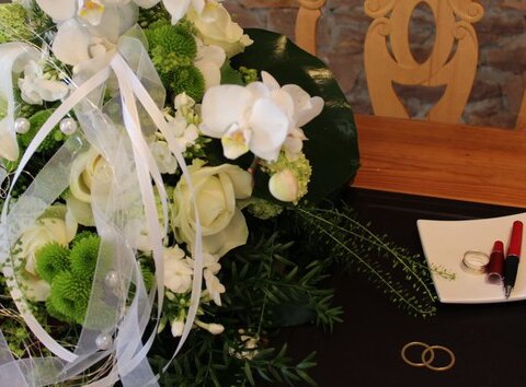 Tisch mit Blumenbouquet, Trauringen und Tintenfüller.