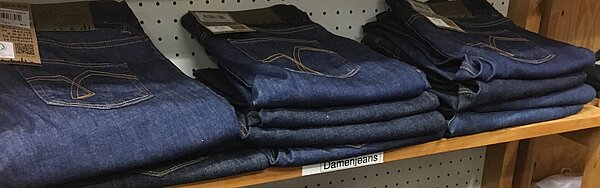 Fair gehandelte Kleidung ausgelegt in einem Regal im Weltladen