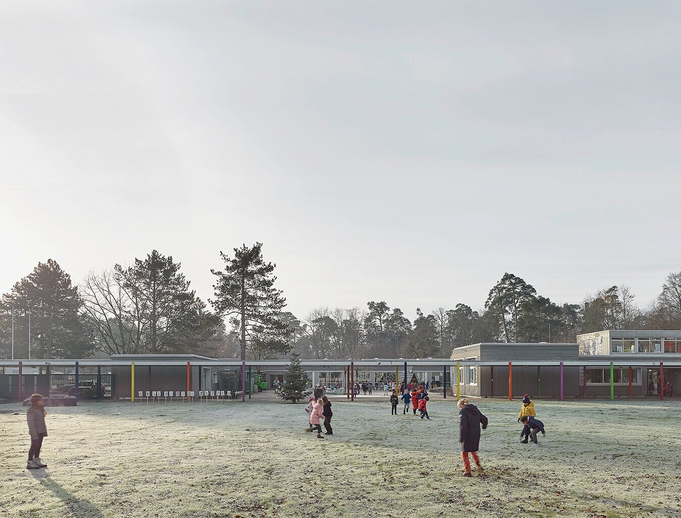 Zu sehen ist der Schulhof mit spielenden Kindern sowie Teile der Fassade.