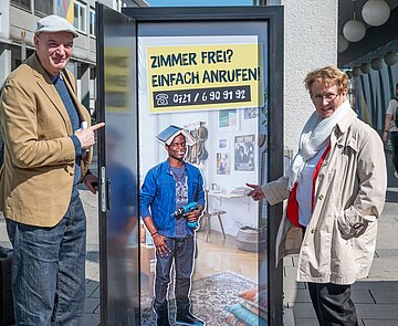 Michael Postert (links), Geschäftsführer des Studierendenwerks, und Bürgermeisterin Gabriele Luczak-Schwarz stellen eine der Türen der Kampagne "Dach gesucht" auf dem Marktplatz vor. 