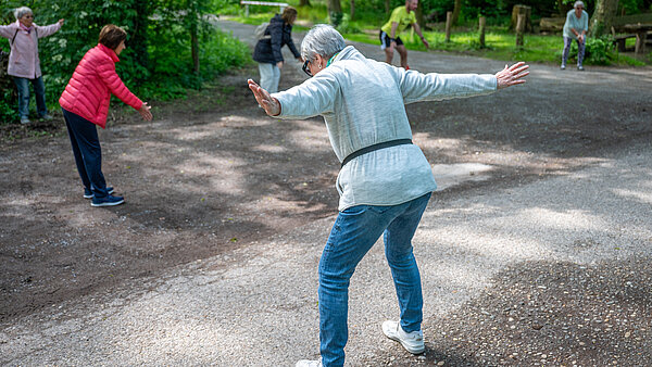 Personen stehen im Wald und führen Rücken-Übungen durch