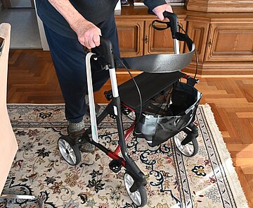 Mann mit Rollator in einem Wohnzimmer.