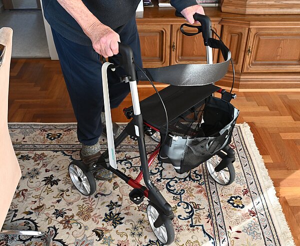 Mann mit Rollator in einem Wohnzimmer.