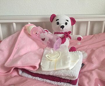 Ein Spielzeugteddy liegt in einem Kinderbett. 