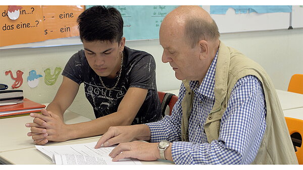 Das Bild zeigt einen Coach mit einem Jugendlichen.