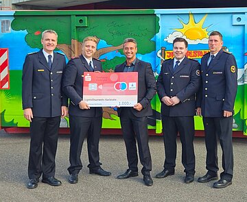 Symbolische Scheckübergabe bei der Hauptfeuerwache (von links: Florian Geldner, Amtsleiter der Branddirektion Karlsruhe; Phillip Hinz, Stadtjugendfeuerwehrwart der Jugendfeuerwehr Karlsruhe; Benjamin Rieth, Regionaldirektor Nord der Sparkasse Karlsruhe; Tim Rothfuß, Beisitzer Jugendfeuerwehr Karlsruhe; Dirk Bertram, stellv. Amtsleiter der Branddirektion Karlsruhe).