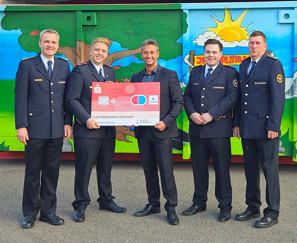 Symbolische Scheckübergabe bei der Hauptfeuerwache (von links: Florian Geldner, Amtsleiter der Branddirektion Karlsruhe; Phillip Hinz, Stadtjugendfeuerwehrwart der Jugendfeuerwehr Karlsruhe; Benjamin Rieth, Regionaldirektor Nord der Sparkasse Karlsruhe; Tim Rothfuß, Beisitzer Jugendfeuerwehr Karlsruhe; Dirk Bertram, stellv. Amtsleiter der Branddirektion Karlsruhe).