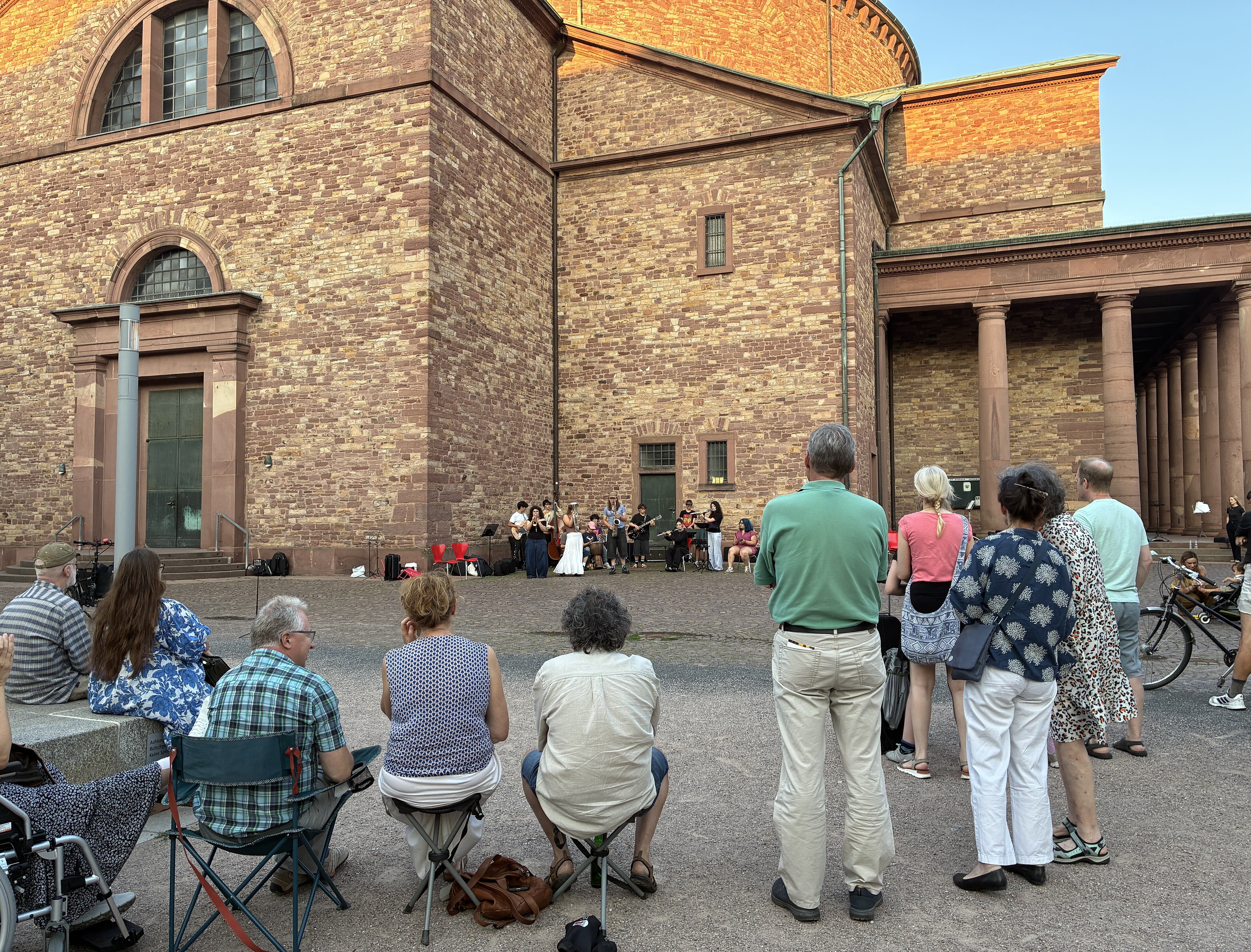 Menschen schauen das Konzert auf Klappstühlen an.