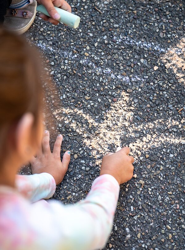 Mädchen bemalt mit Kreide die Starße