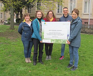 Sonja Mohr-Stockinger (2.v.l.) vom Wettbewerb „Naturstadt“ übergibt Bürgermeisterin Bettina Lisbach (rechts) das offizielle Auszeichnungs-Schild.
