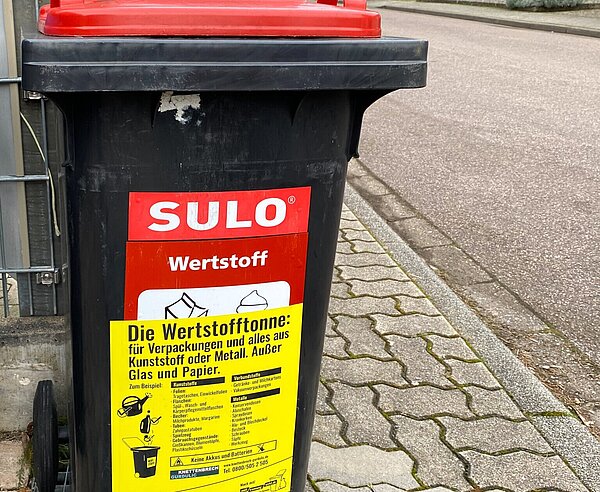 Wertstofftonne mit Gurdulic Aufkleber steht am Straßenrand