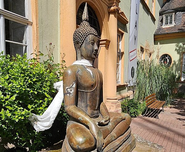 Buddha-Statue vor einer Häuserfassade
