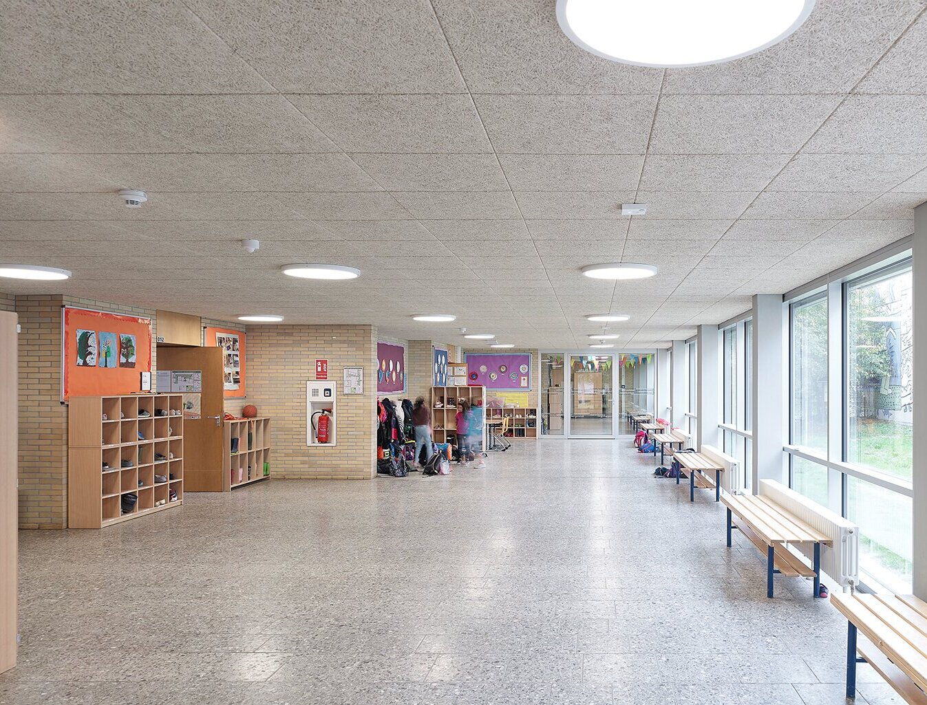 Zu sehen ist der Flurbereich mit Holzwolle-Akustikplatten an der Decke sowie die Garderobe mit verschiedenen Ablageflächen.