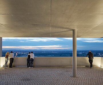 Blick von der gepflasterten, überdachten Turmbergterrasse auf Durlach und die Fächerstadt bei Dämmerung.