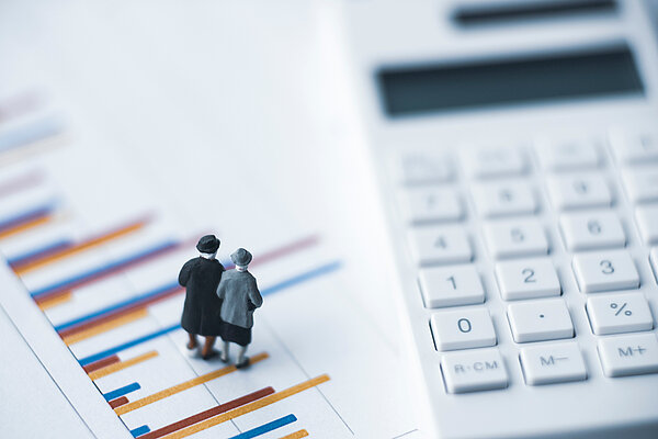 Nahaufnahme eines Taschenrechners mit Mniaturfiguren daneben.