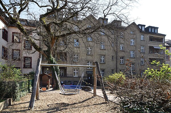 Gebäudeansicht Kita Lessingstraße mit Schaukel im Vordergrund