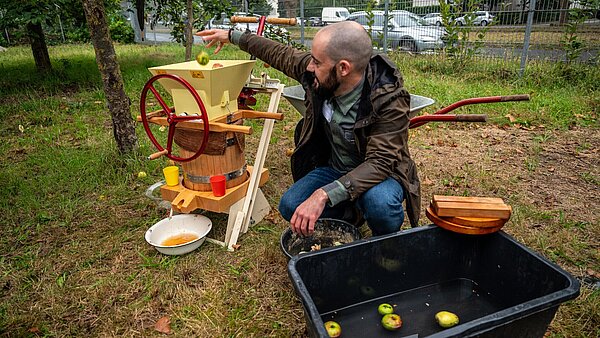 Mann wirft Apfel in den Entsafter