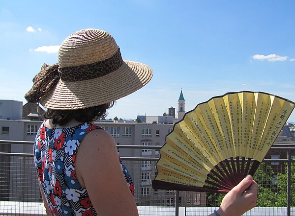 Frau von hinten mit Sonnenhut und Fächer