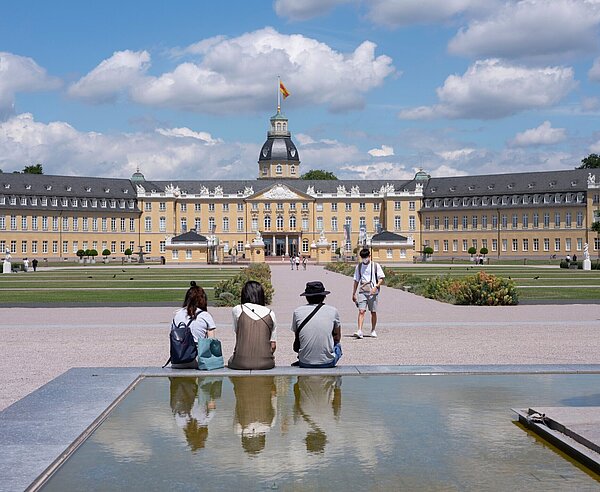 Sitzende Menschen schauen sich das Schloss an