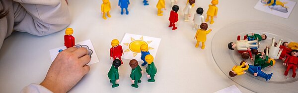 Konfliktsituation zwischen Schülern und Schülerinnen wird mit Spielfiguren am Tisch nachstellt