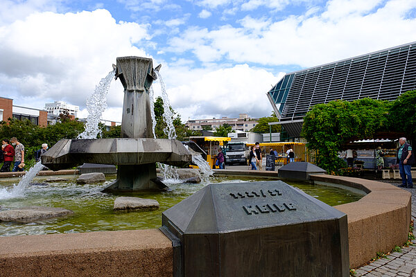 Das Bild zeigt den Bettel-Brunnen von Rainer Scheithauer auf dem Neureuter Platz.