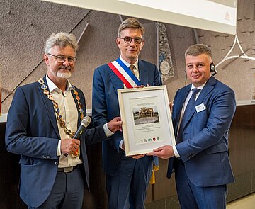 Trilaterale Freundschaft bekräftigt: Die Oberbürgermeister Mentrup und Klein präsentieren mit Winnyzjas Stadtratsvorsitzendem Pavlo Yablonskyi (v.l.) ein Bild des Jubläumsgeschenks.