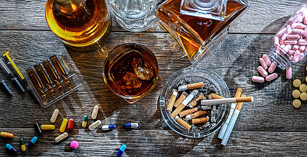 Suchtmitte wie Tabletten, Spritzen, Alkohol und Zigaretten liegen auf einem Tisch