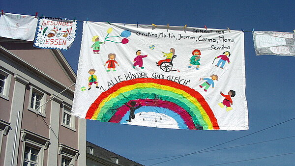 Transparente zum Weltkindertag an einer Leine hängend vor dem Rathaus – von Kindern gestaltet.