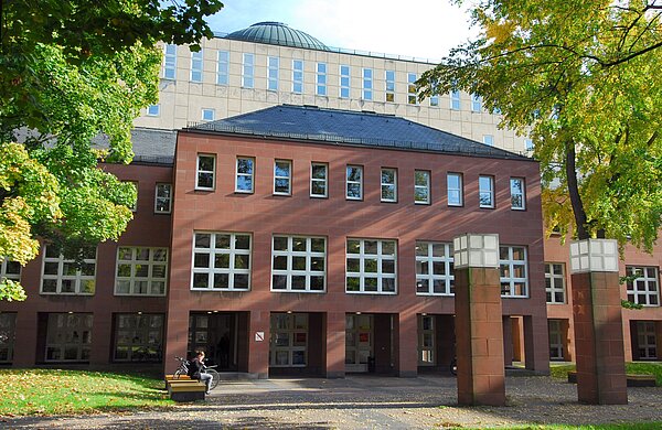 Der Eingang des Badischen Landesbibliothek eingerahmt von Bäumen.