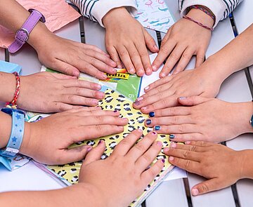 Kinder legen ihre Hände alle in die Tischmitte