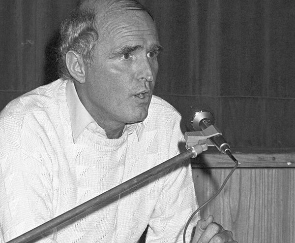 Dieter Stoltz im Dezember 1984 bei einem Redebeitrag vor einem Mikrofon sitzend.