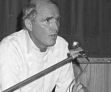 Dieter Stoltz im Dezember 1984 bei einem Redebeitrag vor einem Mikrofon sitzend.