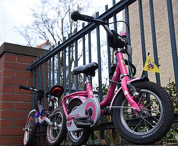 Kinderfahrräder parken auf Mauer angeschlossen an Geländer