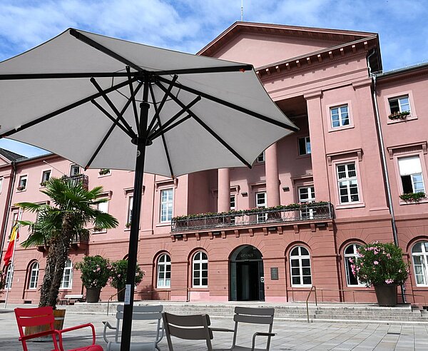 Sitzmöglichkeiten unter Sonnenschirmen umgeben von Palmen auf dem Marktplatz vor dem Rathaus