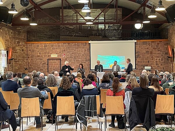 Sicht über die vollen Reihen der Besucher zur Podiumsdiskussion