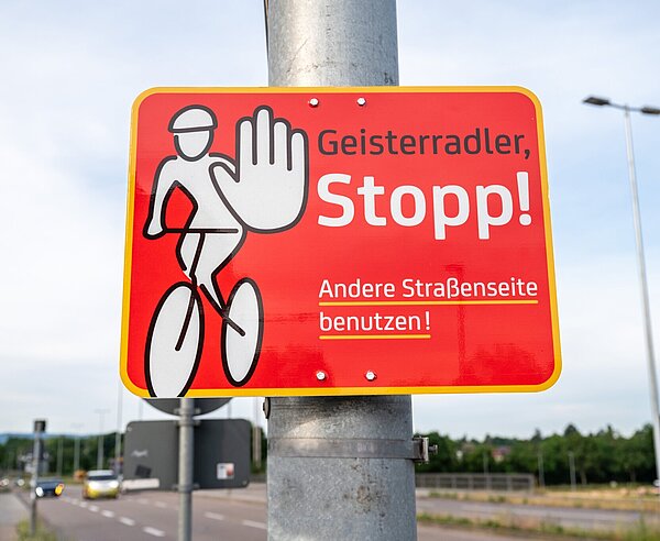 Ein Hinweisschild an einem Mast weist auf die Gefahr von Geisterradlern hin