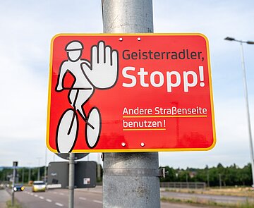 Ein Hinweisschild an einem Mast weist auf die Gefahr von Geisterradlern hin